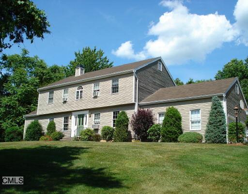 a view of a white house next to a yard with big trees