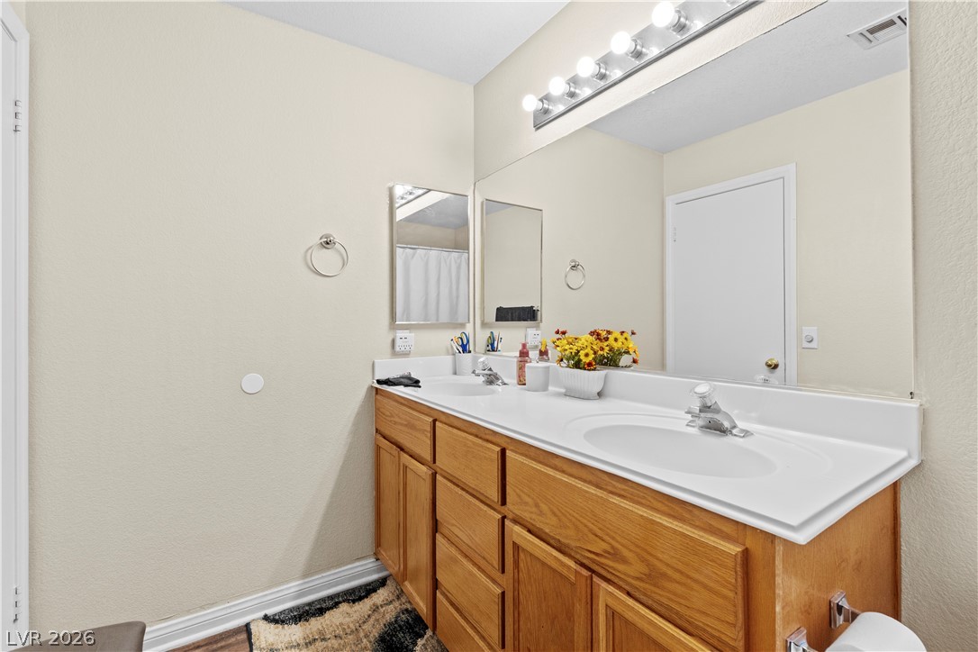 1419 Red Sunset Avenue Henderson, NV 89074 - Photo 22 of 35 Full bathroom with double vanity, a textured wall, and a shower with shower curtain