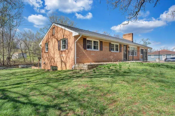 a view of a house with a yard and large tree