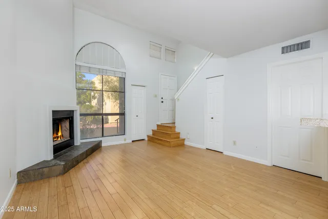 a big room with wooden floor fireplace and windows