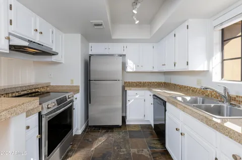 a kitchen with granite countertop a sink stove and refrigerator