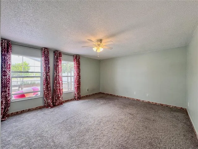 an empty room with windows and chandelier fan