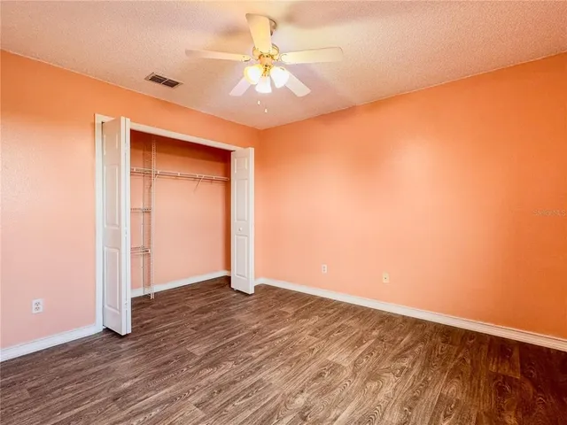 an empty room with wooden floor and fan