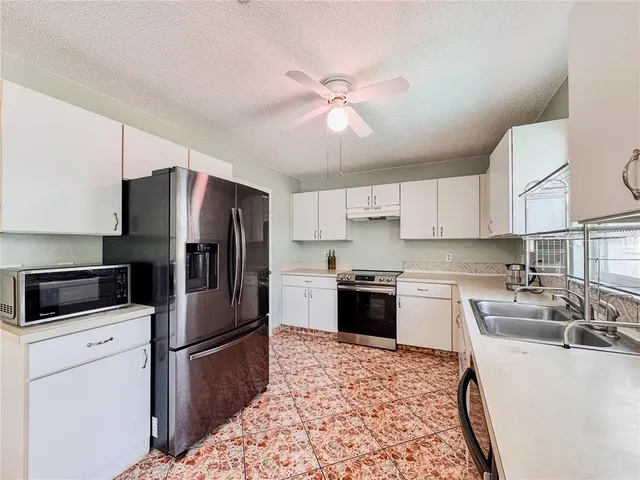 a kitchen with granite countertop a refrigerator stove top oven and sink