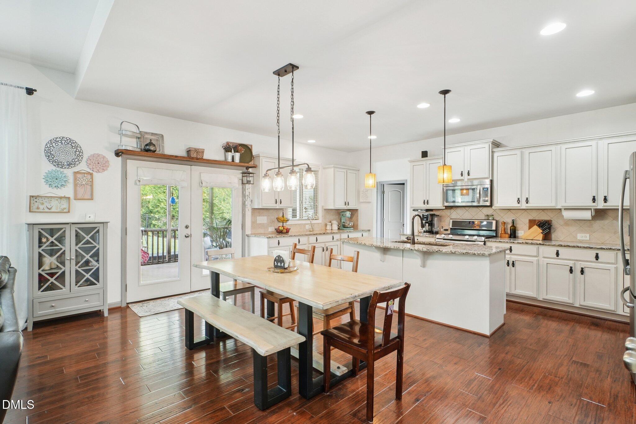 203 Hico Way Durham, NC 27703 - Photo 11 of 62 a kitchen with stainless steel appliances granite countertop a stove a refrigerator a kitchen island with white cabinets and wooden floor