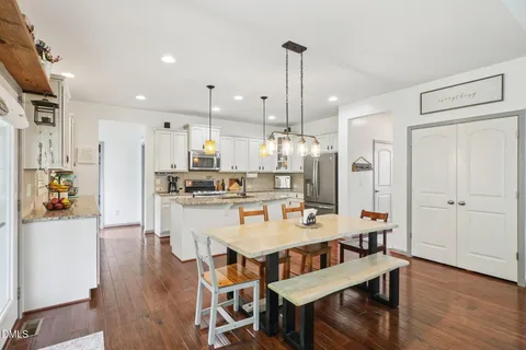 a kitchen with stainless steel appliances granite countertop a refrigerator a sink a stove and a wooden floors