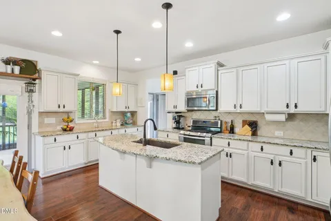 a kitchen with stainless steel appliances granite countertop a sink a stove and chairs