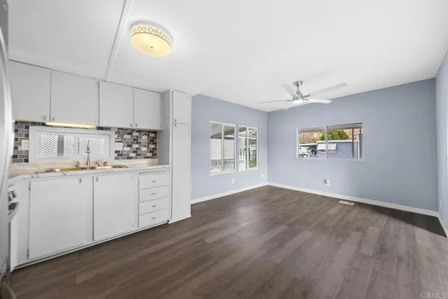 a kitchen with cabinets wooden floor and a window