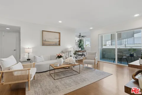 a living room with furniture a glass table and a large mirror with potted plants