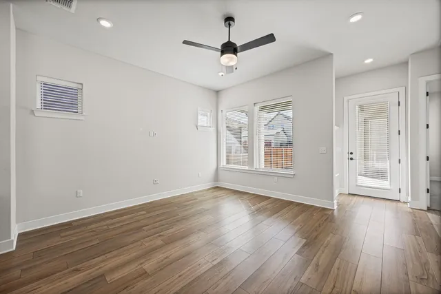 a view of an empty room with a window and wooden floor