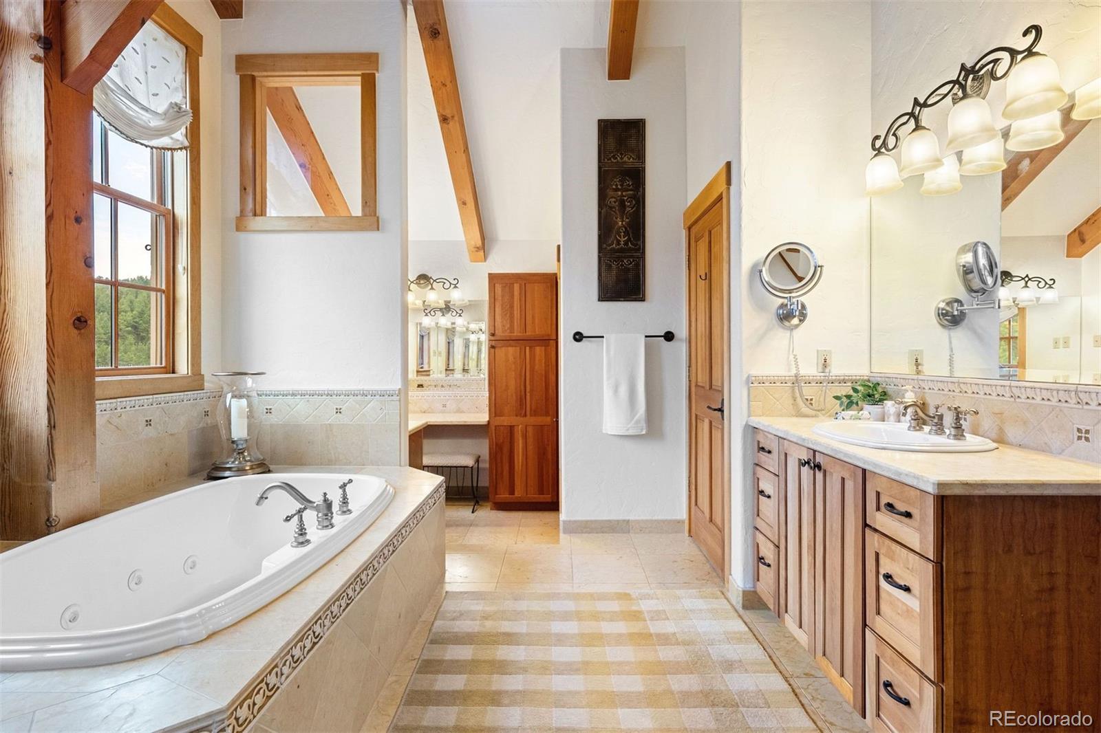 80 Elk Crossing Lane Evergreen, CO 80439 - Photo 26 of 49 a bathroom with a tub sink and mirror