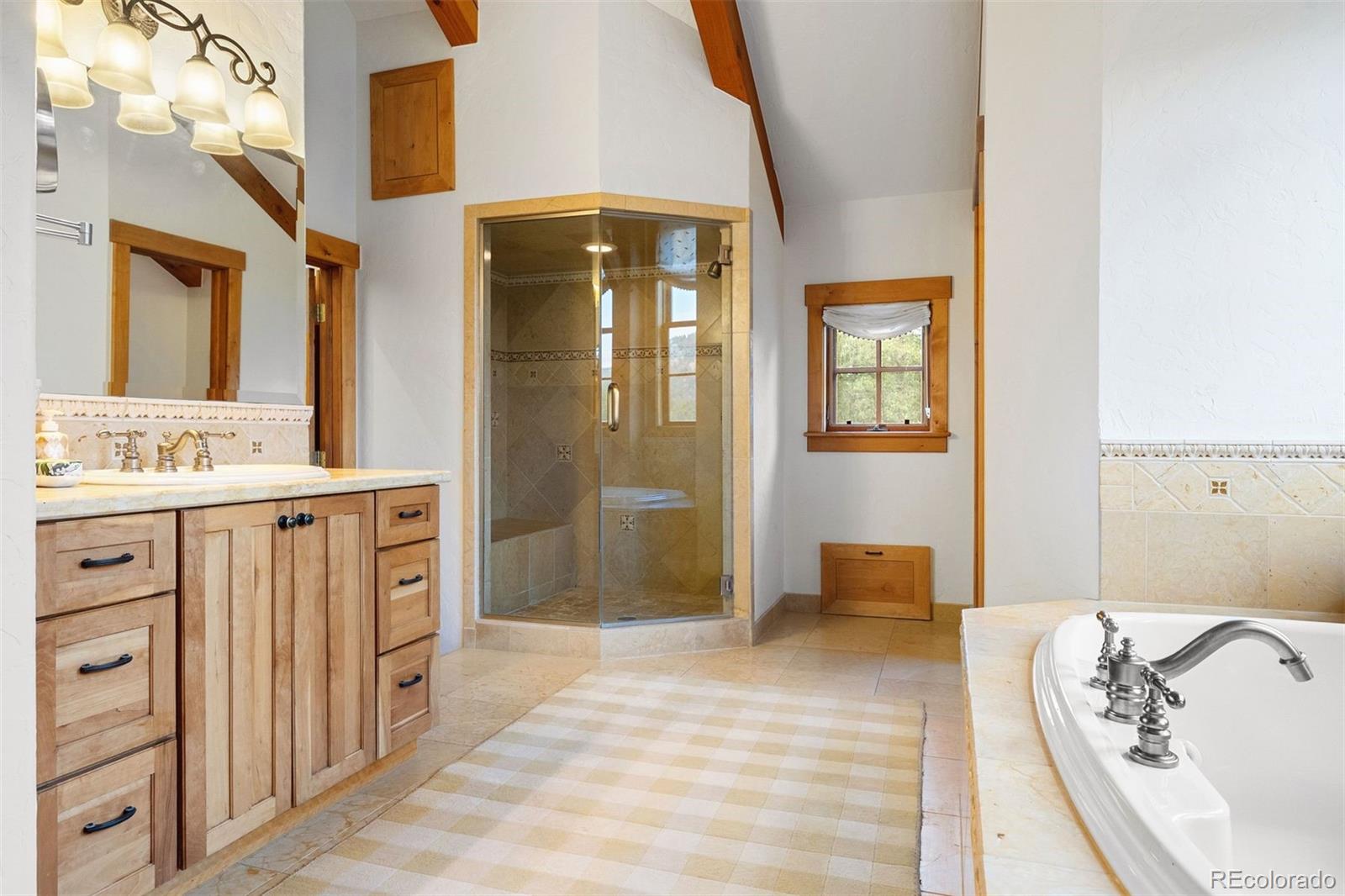 80 Elk Crossing Lane Evergreen, CO 80439 - Photo 27 of 49 a spacious bathroom with a mirror a sink and a shower