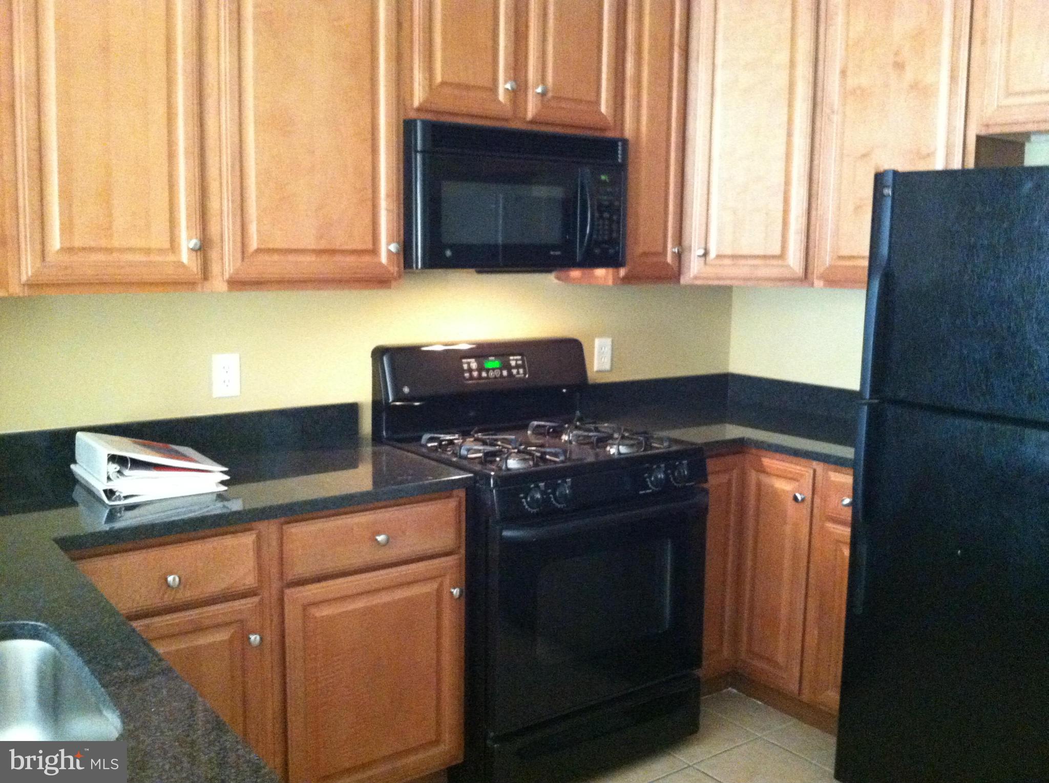 8045 Newell Street, Unit 203 Silver Spring, MD 20910 - Photo 7 of 11 a kitchen with granite countertop cabinets and black appliances