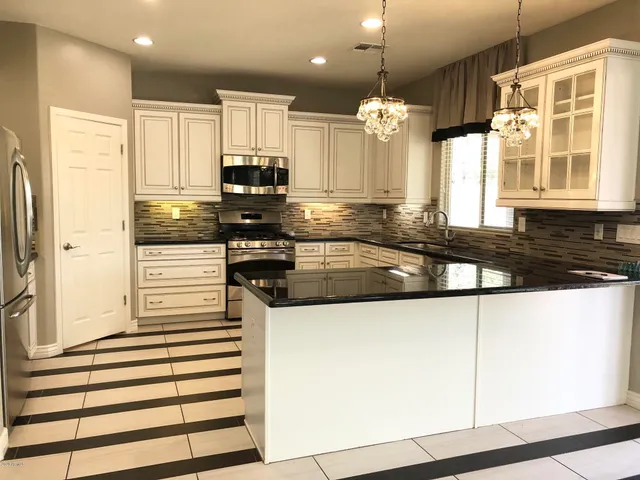 a kitchen with stainless steel appliances granite countertop a sink a stove and a refrigerator