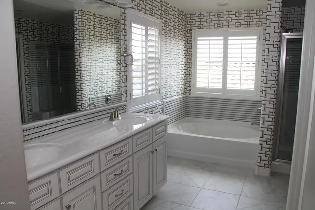 a bathroom with a granite countertop sink a bathtub and next to a window