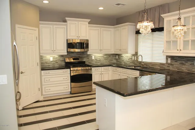 a kitchen with stainless steel appliances granite countertop a sink a stove and cabinets