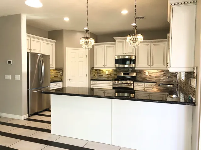 a kitchen with stainless steel appliances granite countertop a refrigerator a sink and a stove