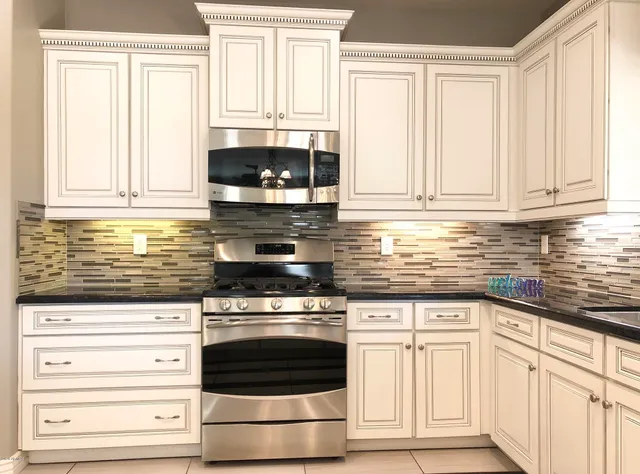 a kitchen with granite countertop white cabinets and stainless steel appliances