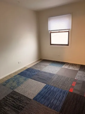 an empty room with wooden floor cabinet and windows
