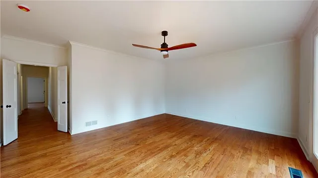 an empty room with wooden floor windows and entrance