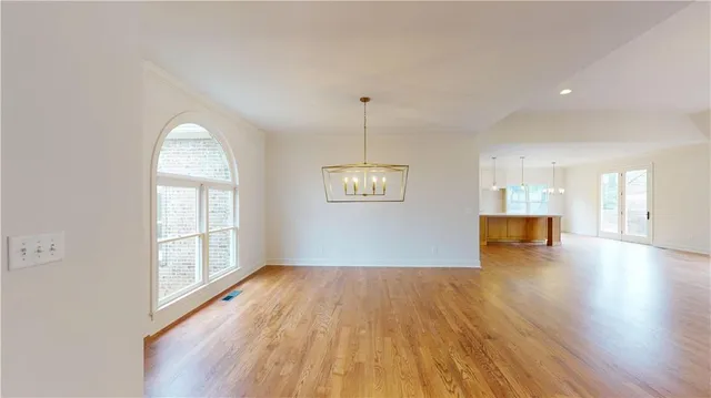 a view of an empty room with wooden floor and a fireplace