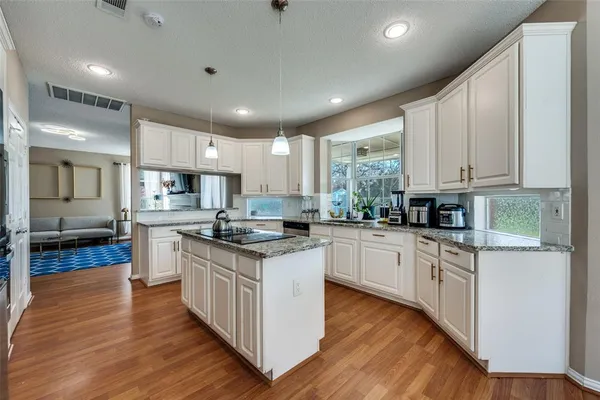 a kitchen with granite countertop sink stove and white cabinets with wooden floor