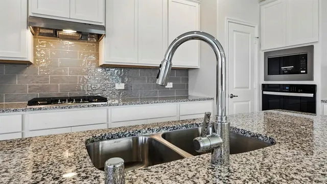 a kitchen with a stove a faucet and a sink
