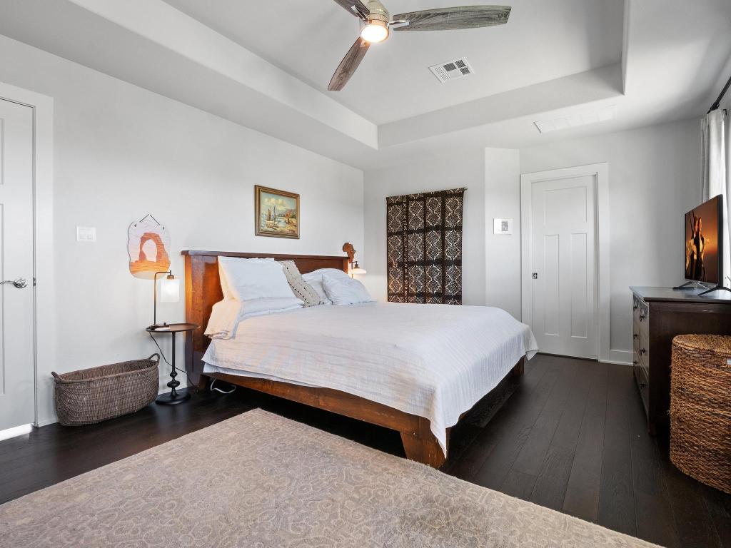 10103 Twin Lake Loop Dripping Springs, TX 78620 - Photo 21 of 32 Bedroom featuring dark wood-style flooring, a tray ceiling, baseboards, and a ceiling fan