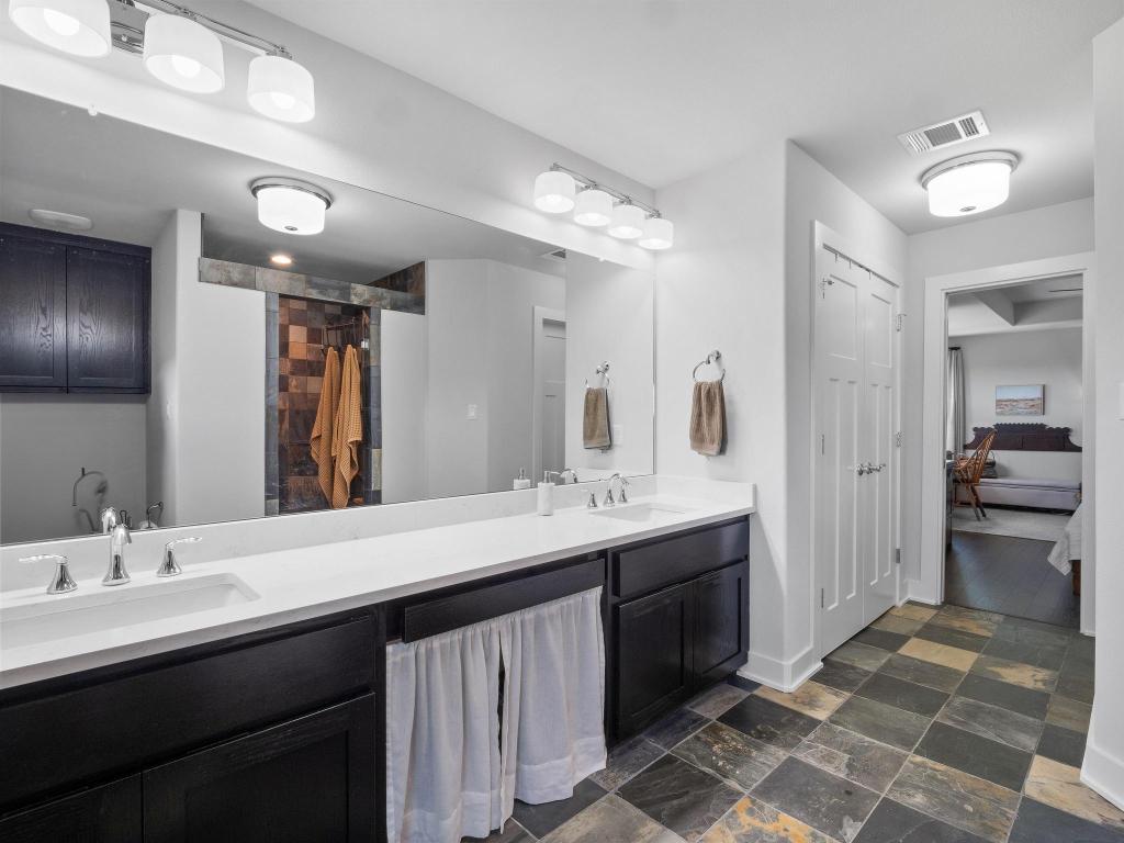 10103 Twin Lake Loop Dripping Springs, TX 78620 - Photo 25 of 32 Ensuite bathroom featuring double vanity, stone tile floors, baseboards, and a shower with curtain