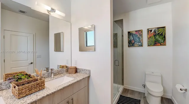 a bathroom with a granite countertop sink mirror vanity and toilet