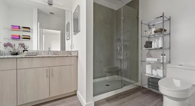 a bathroom with a granite countertop sink a toilet and shower