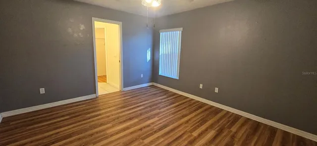 a view of an empty room with wooden floor and a window