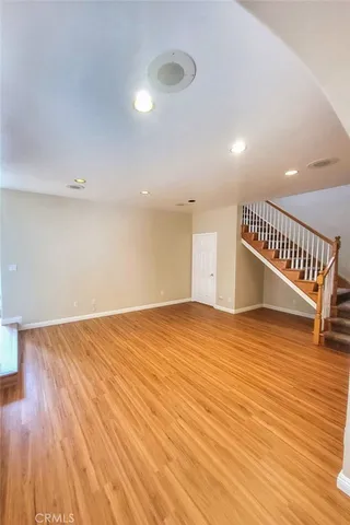 a view of an empty room with wooden floor and staircase