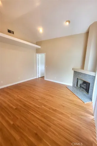 a view of an empty room with wooden floor and a fireplace