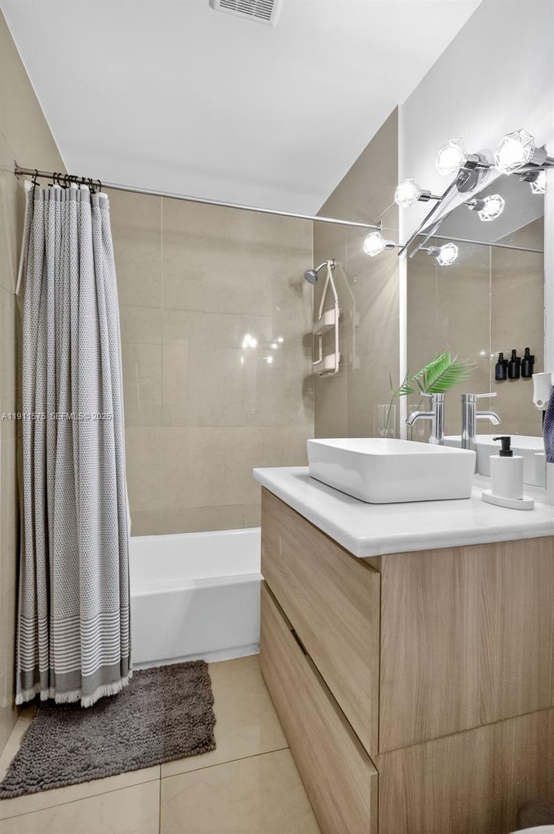 765 Northwest 46th Street Miami, FL 33127 - Photo 16 of 40 a bathroom with a granite countertop sink a mirror and a bathtub