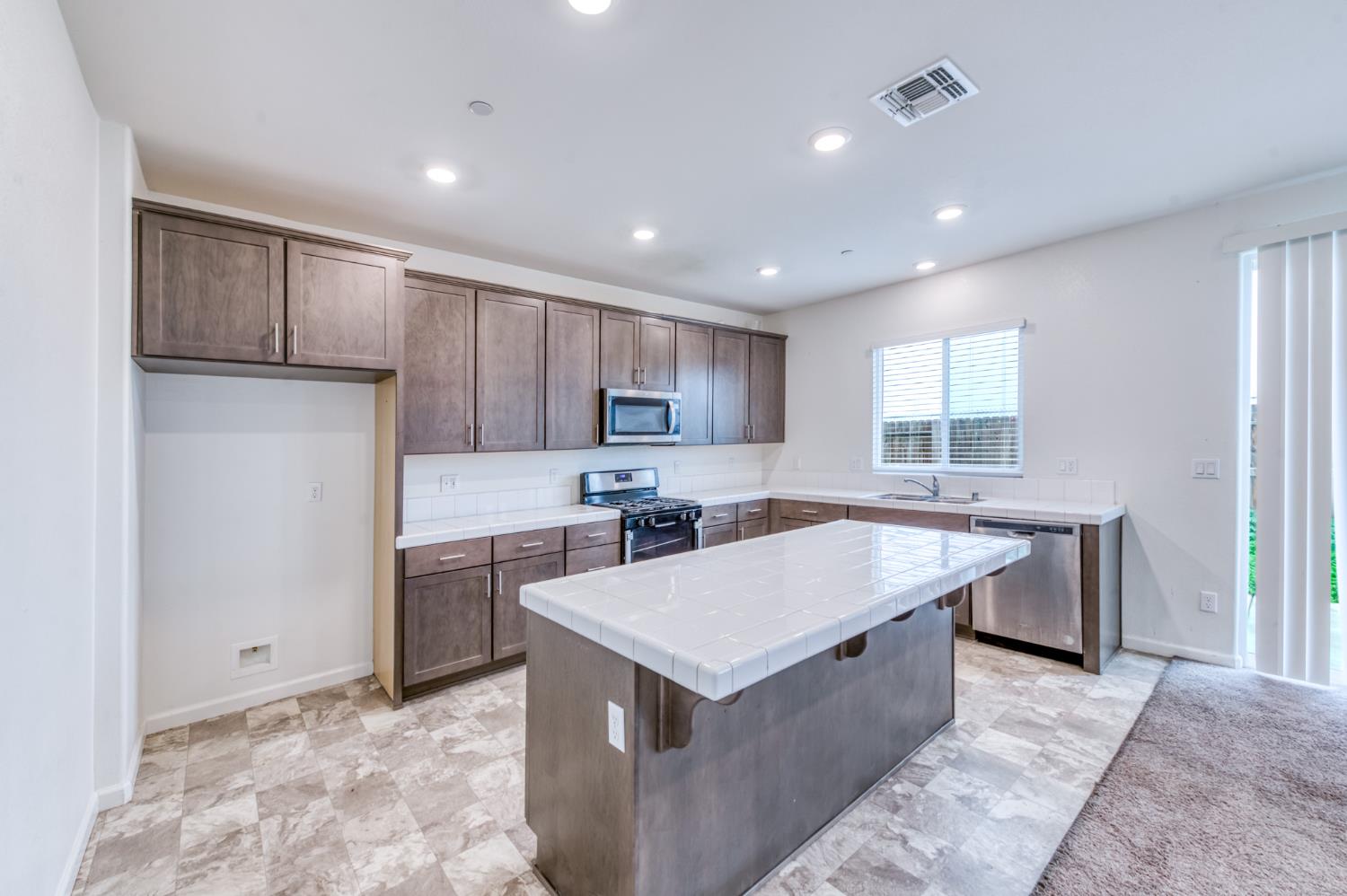 1469 Rinconada Drive Madera, CA 93637 - Photo 13 of 32 a kitchen with kitchen island a sink appliances and cabinets
