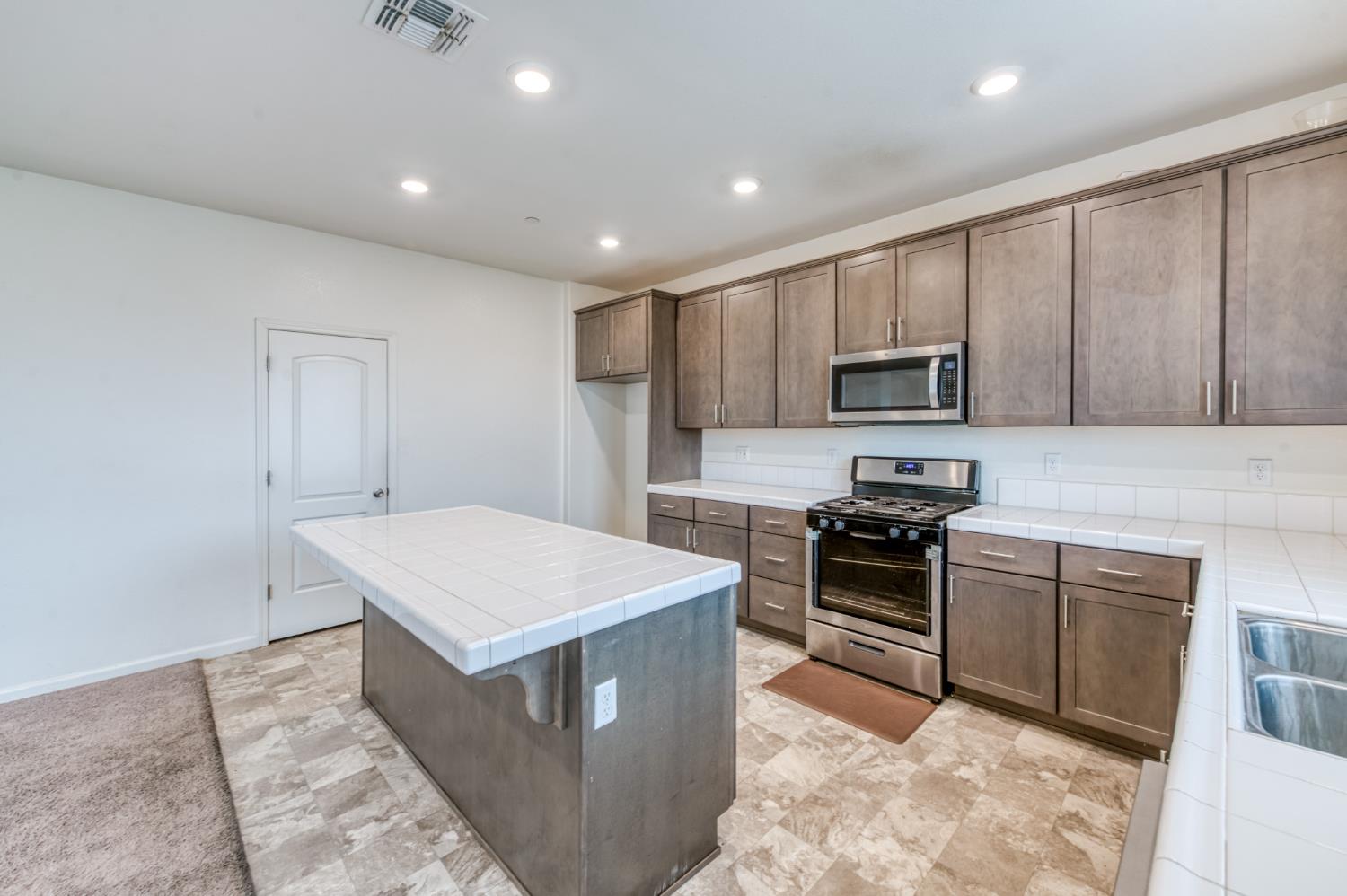 1469 Rinconada Drive Madera, CA 93637 - Photo 14 of 32 a kitchen with a stove a sink and a refrigerator