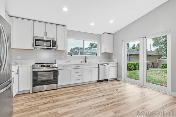 a kitchen with stainless steel appliances a stove top oven a sink and a refrigerator