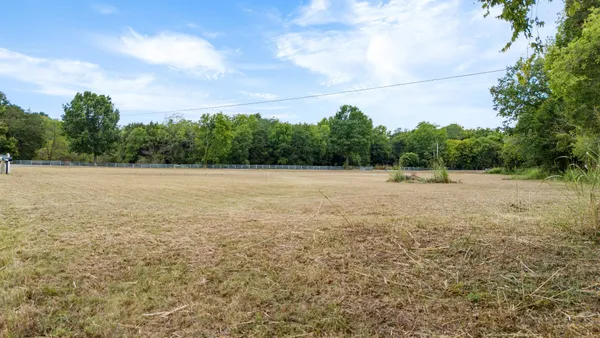 a view of a field with an trees in the background