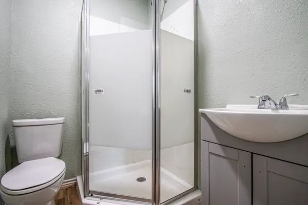 a bathroom with a sink a toilet and shower
