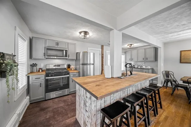 a kitchen with stainless steel appliances granite countertop a stove a refrigerator a sink a dining table and chairs