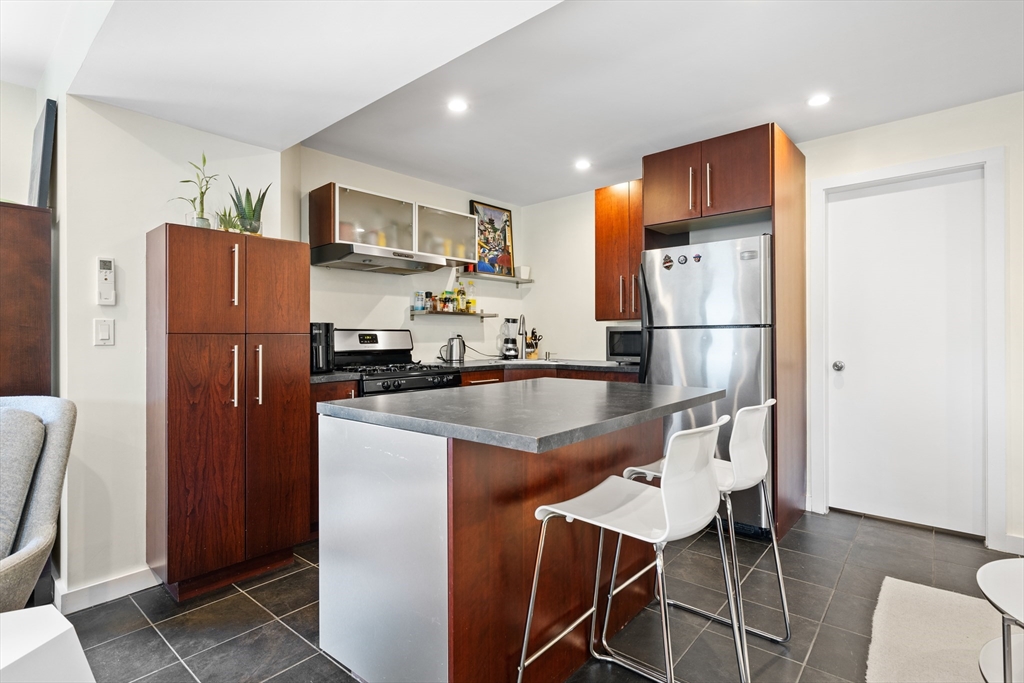 62 Grampian Way, Unit STUDIO Boston, MA 02125 - Photo 8 of 25 a kitchen with stainless steel appliances granite countertop a refrigerator a stove a sink a dining table and chairs