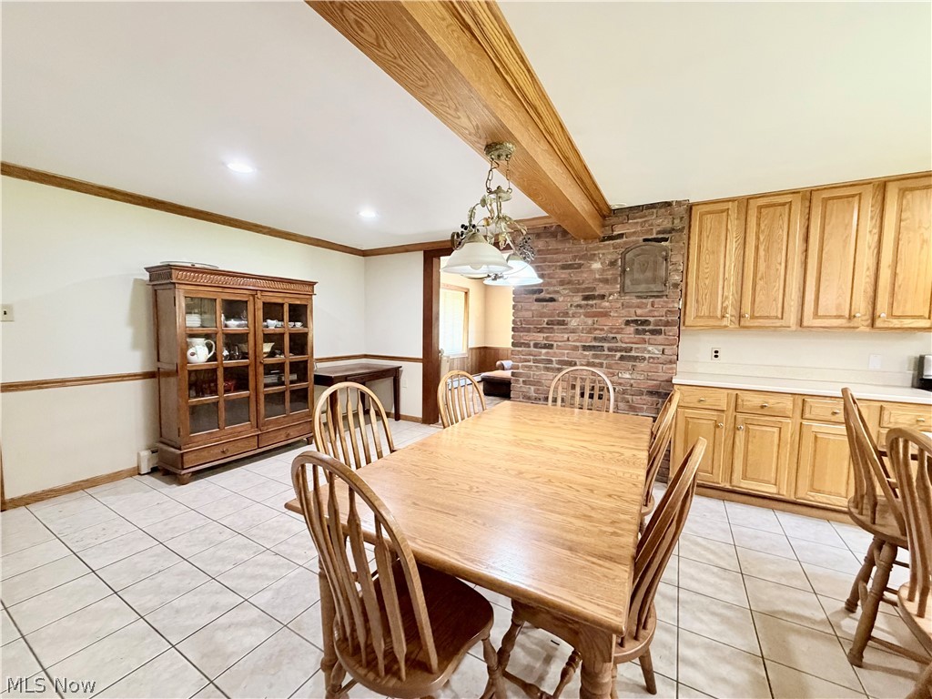 12590 Rockhaven Road Chesterland, OH 44026 - Photo 9 of 25 Spacious room featuring light wood-finish cabinetry, a brick accent wall, and a wood-finish ceiling beam