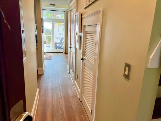 a view of a hallway with wooden floor and a bathroom
