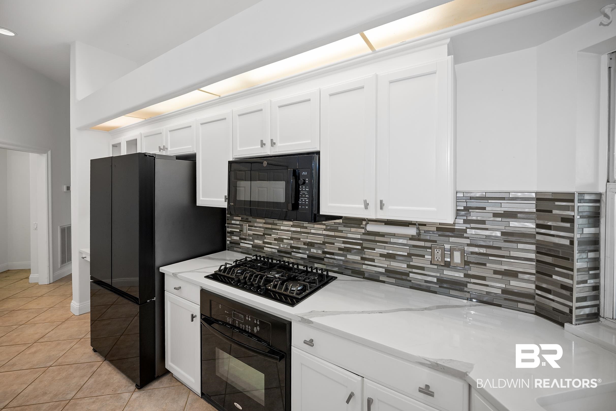 8591 Bay Harbor Road Elberta, AL 36530 - Photo 20 of 56 Kitchen with white cabinetry, black appliances, and light tile patterned flooring