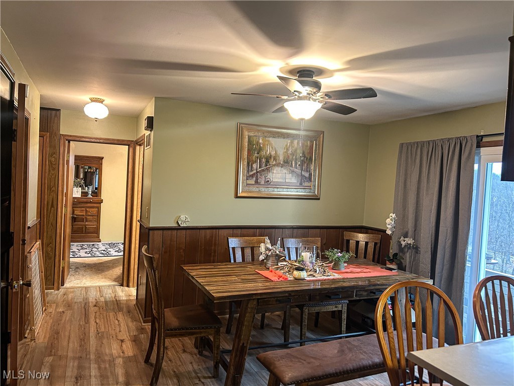 2242 South McCoy Ridge Road Stockport, OH 43787 - Photo 6 of 41 Dining room featuring a wainscoted wall, hardwood / wood-style flooring, wood walls, and a ceiling fan