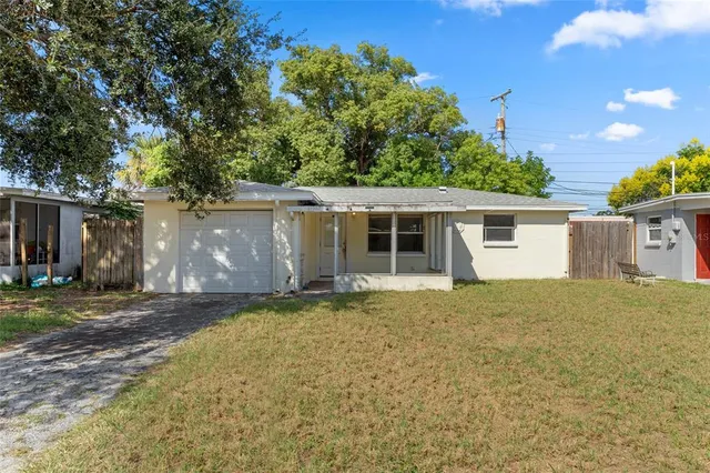 a view of a house with a yard and large tree