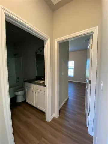 a view of a hallway with wooden floor windows and a kitchen