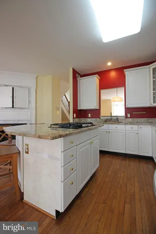 a kitchen with stainless steel appliances granite countertop a sink cabinets and wooden floor
