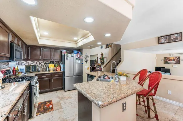 a kitchen with stainless steel appliances granite countertop a sink dishwasher and a refrigerator